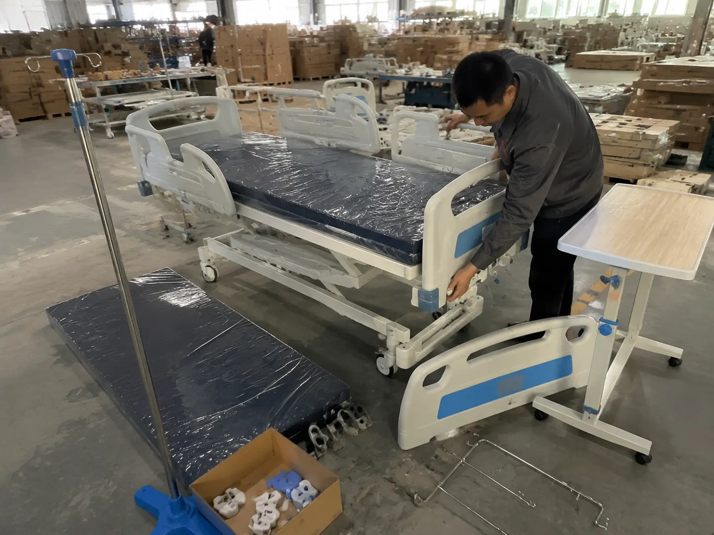 Technician inspecting hospital bed accessories in a medical bed factory